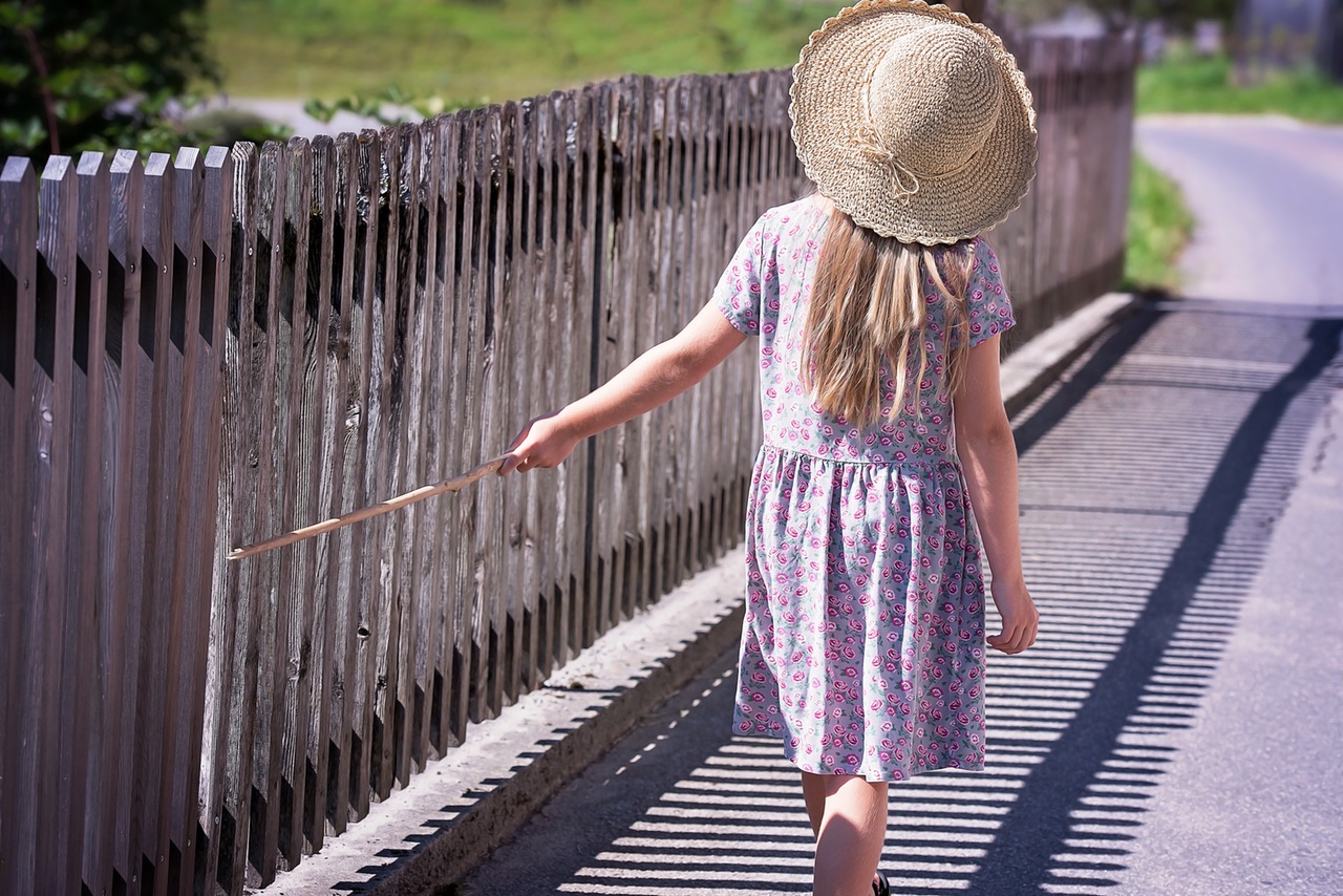 παιδί με καπέλο που περπατά στη γέφυρα και ακουμπάει τα κάγκελα